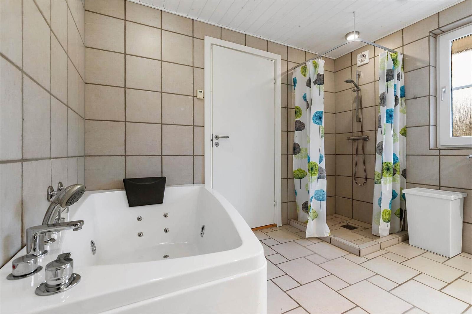 Bad mit Whirlpool, Dusche und Fenster.