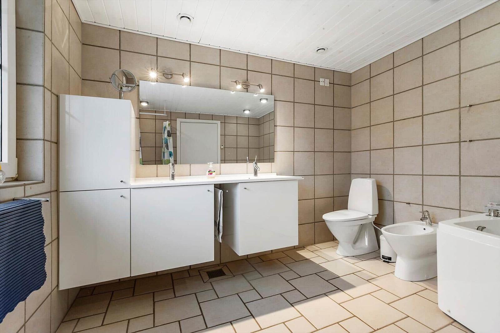 Badezimmer mit Waschbecken, Toilette und Bidet. Fliesen an Wänden und Boden.