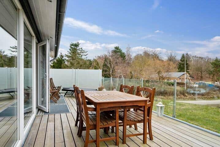 Terrasse mit Holztisch und Stühlen, Blick auf Garten und Wald.