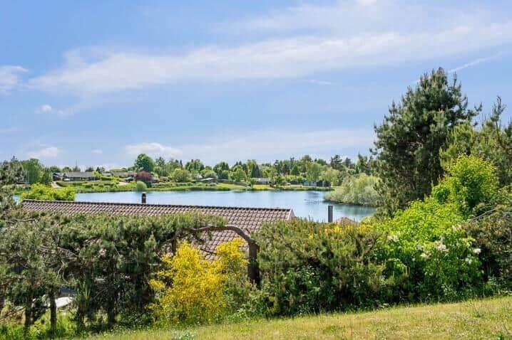Haus mit Blick auf einen ruhigen See, umgeben von grüner Vegetation und Bäumen.