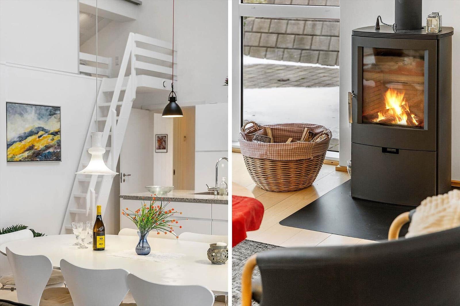 Essbereich mit Tisch und Stühlen, Küche und Treppe. Wohnbereich mit Kamin und Holzkorb.
