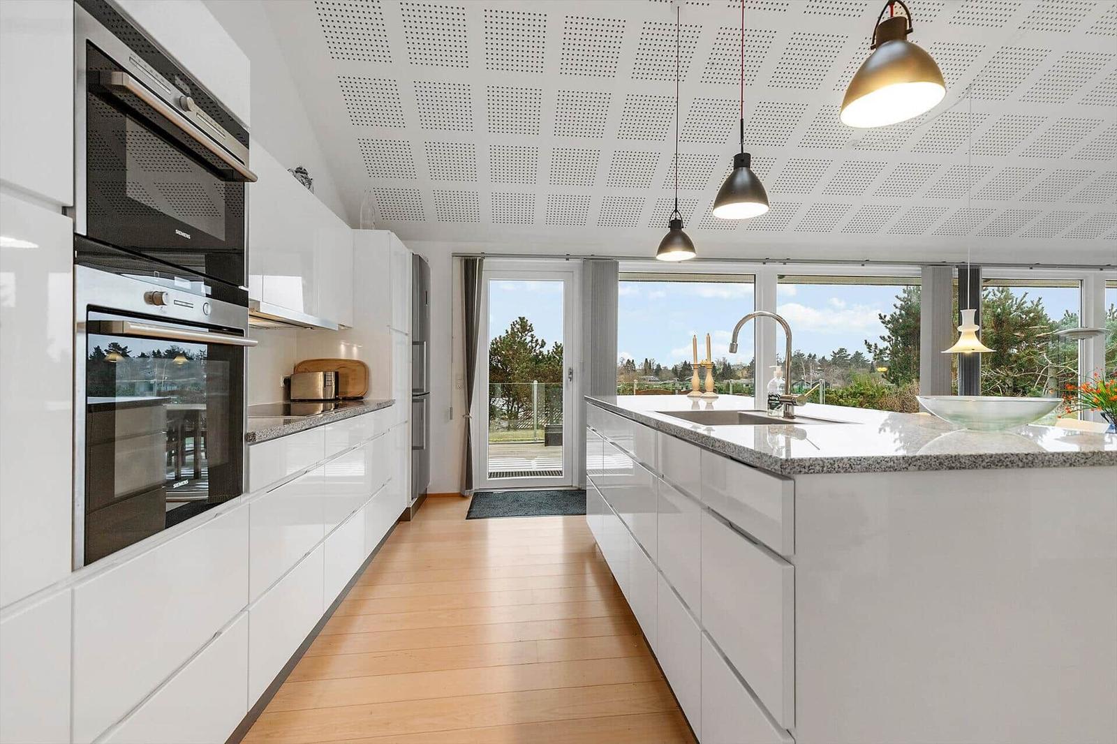 Moderne Küche mit weißer Arbeitsplatte und Blick auf Garten.