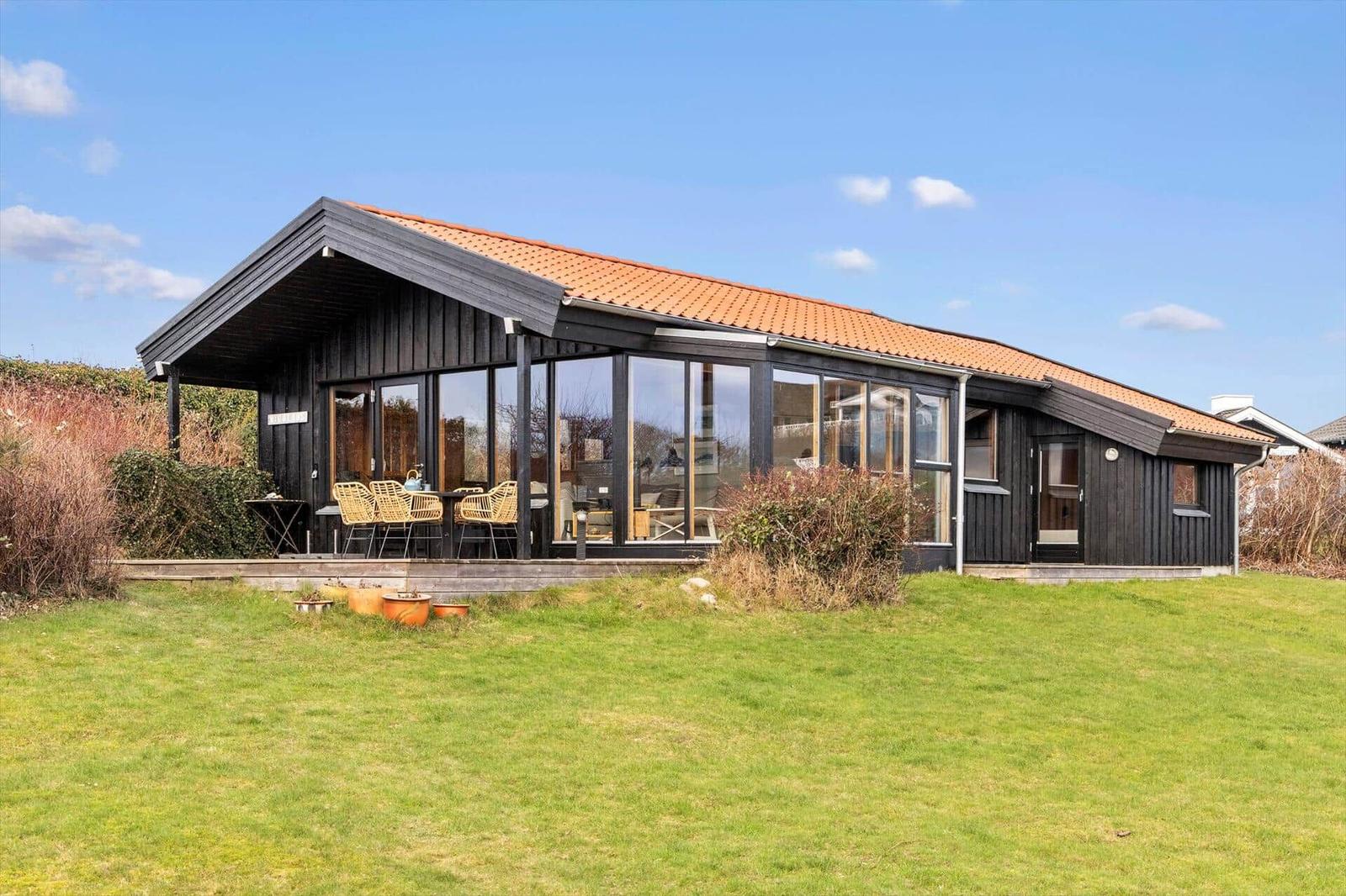 Moderne Holzhütte mit großem Glasbereich und Terrasse im Garten.