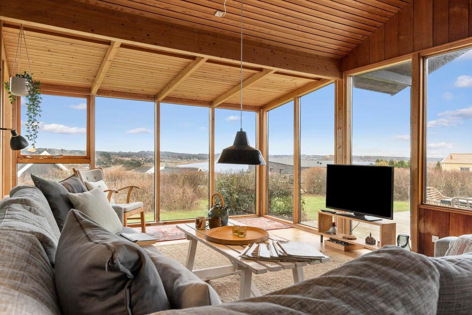 Wohnzimmer mit Holzdecke und großen Fenstern zur Aussicht