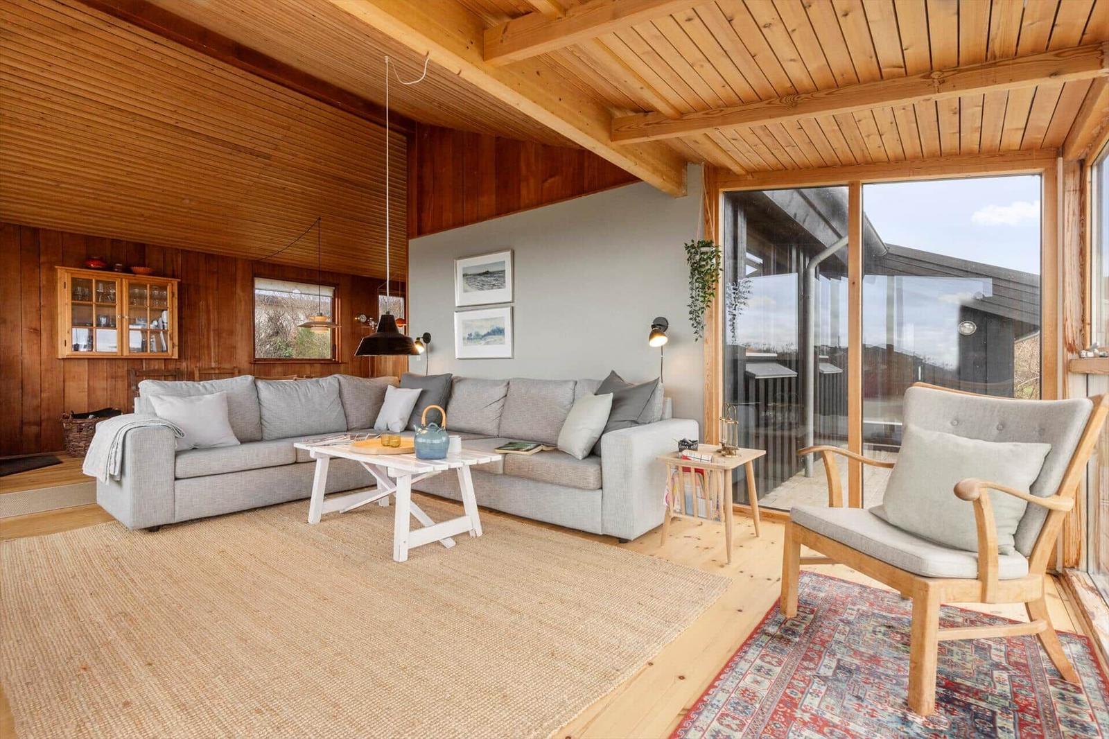 Wohnzimmer mit Sofa, Stuhl und Glasfront zur Terrasse