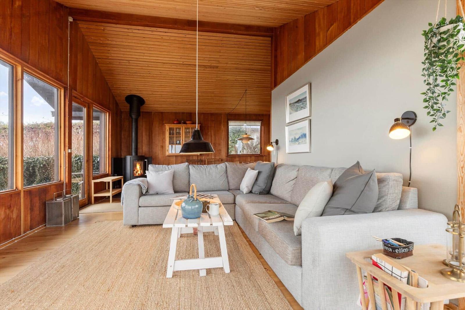 Wohnzimmer mit Sofa, Kamin und Holzwand.