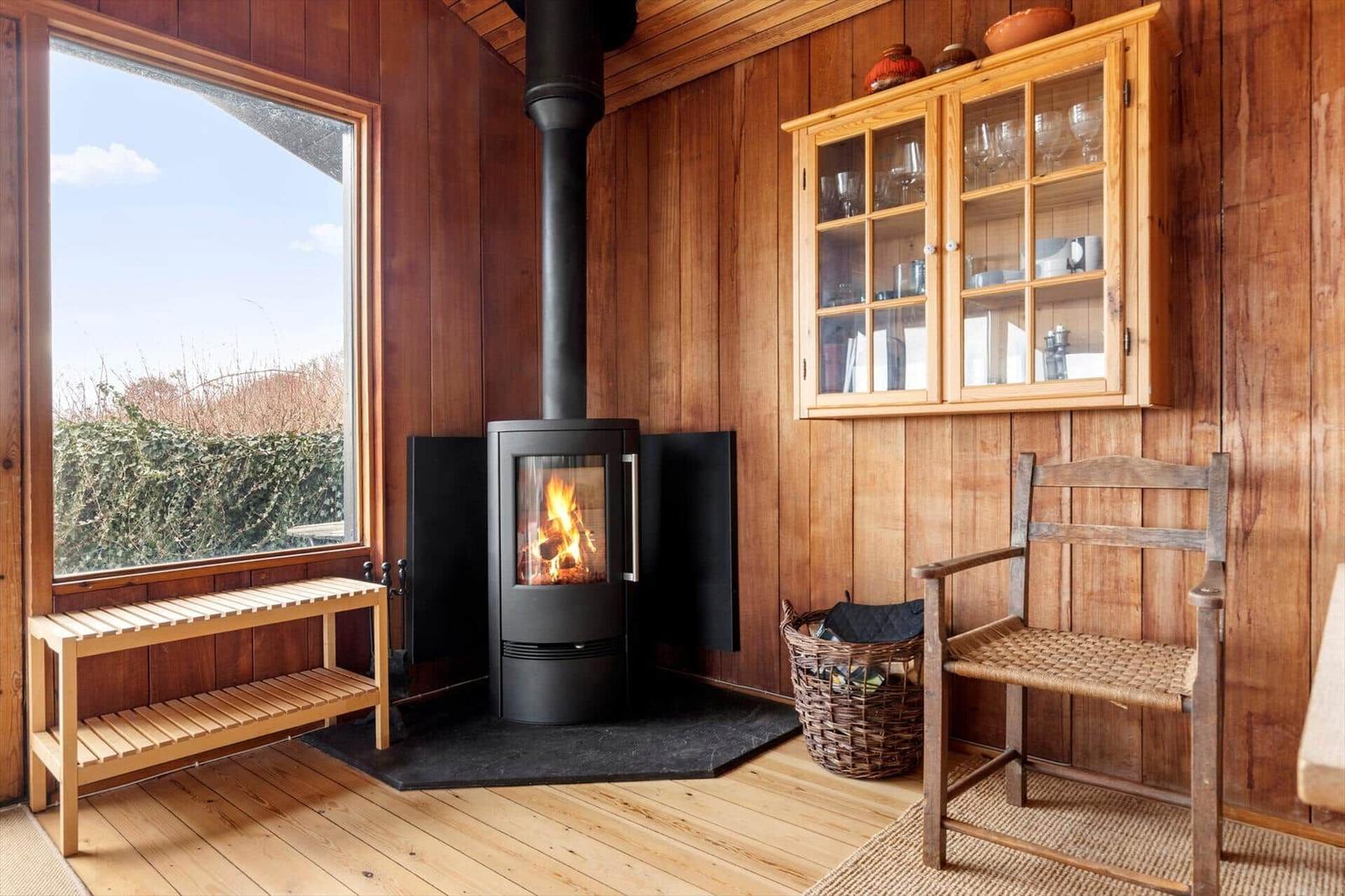 Raum mit Kamin, Holzwand und Fenster zum Blick nach draußen.