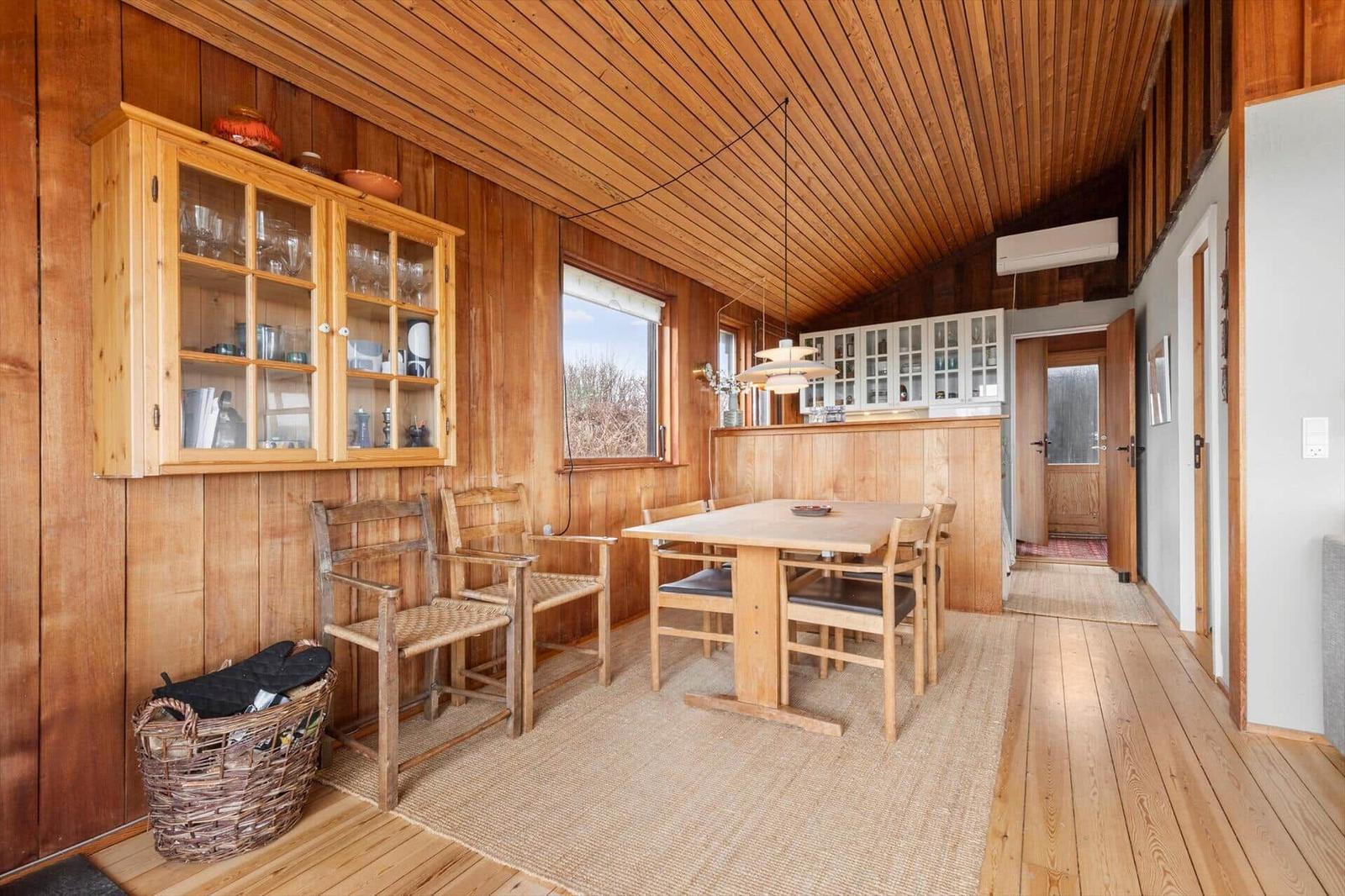 Essbereich mit Holztisch, Stühlen und Glasvitrine an der Wand.