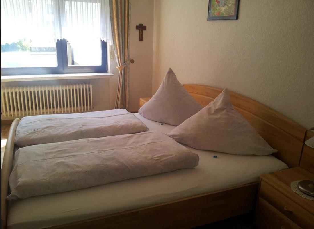 Schlafzimmer mit Holzbett, Fenster und Nachttisch.