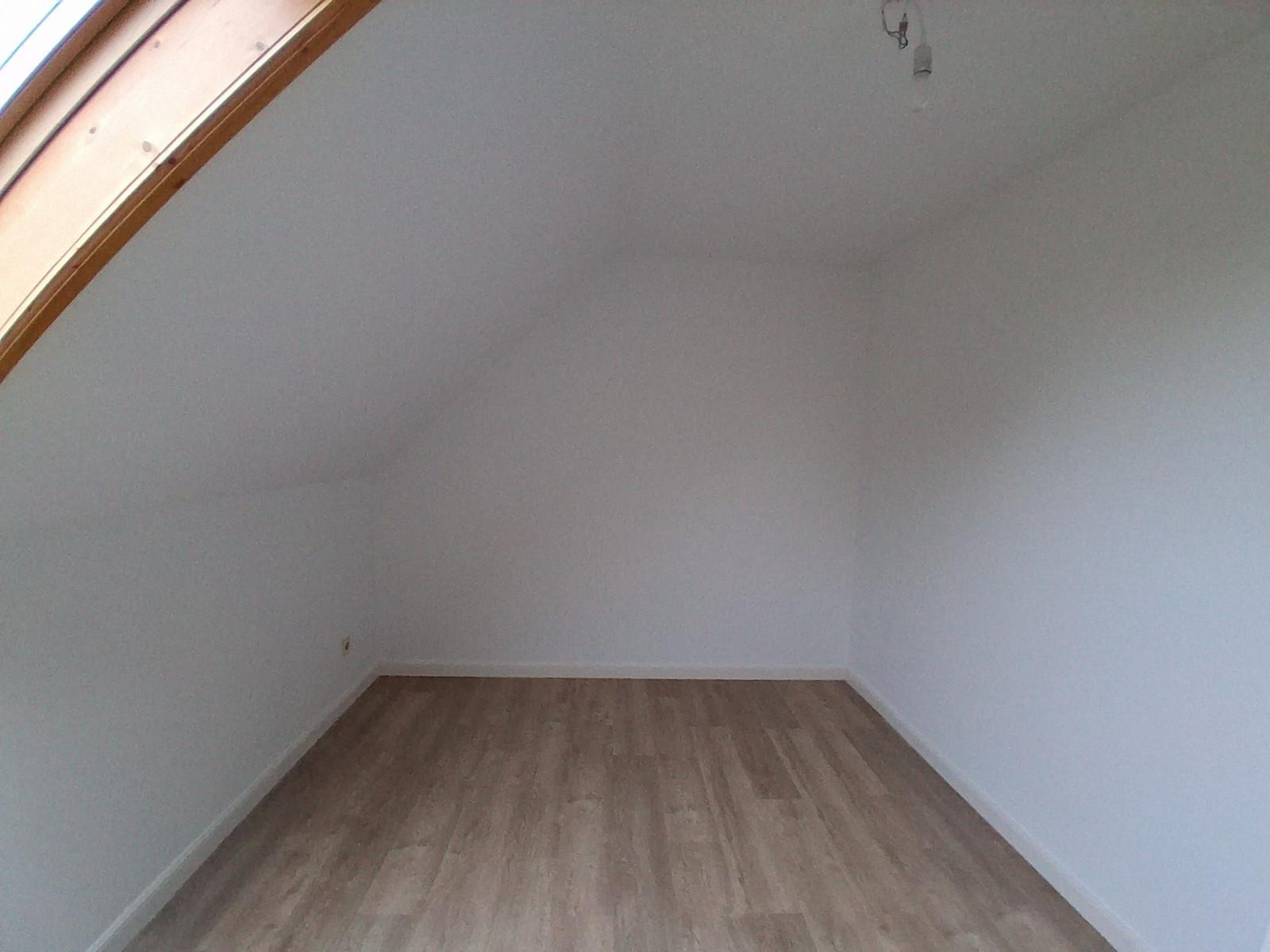 Raum mit Holzfußboden und Dachschrägen, Fenster und Deckenleuchte sichtbar