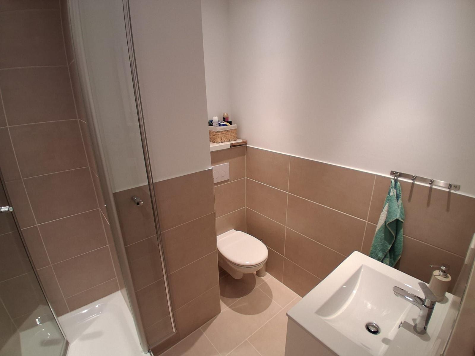 Badezimmer mit Dusche, Toilette und Waschbecken.