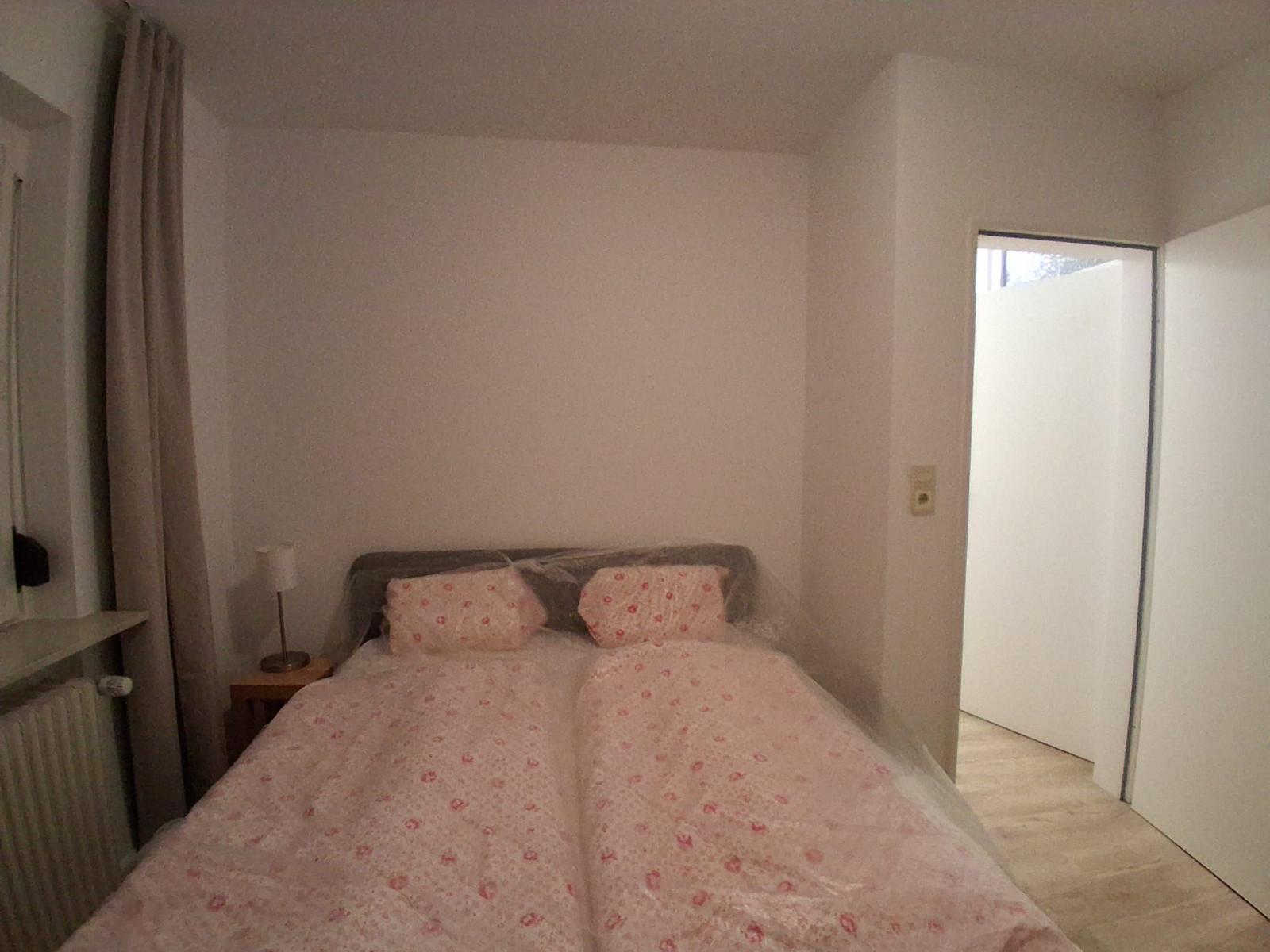 Schlafzimmer mit Bett, Nachttisch und Fenster