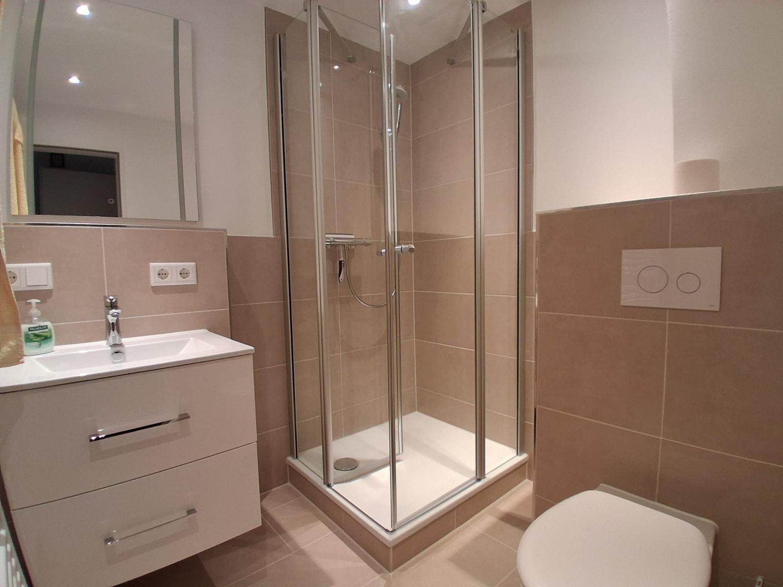 Badezimmer mit Dusche, Waschbecken und Toilette.