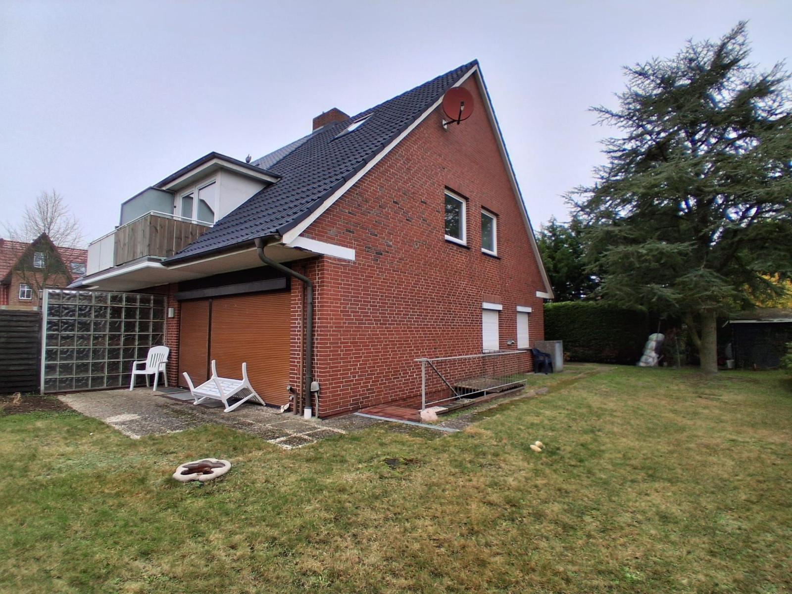 Rotes Backsteinhaus mit Garten, Garage und Satellitenschüssel.