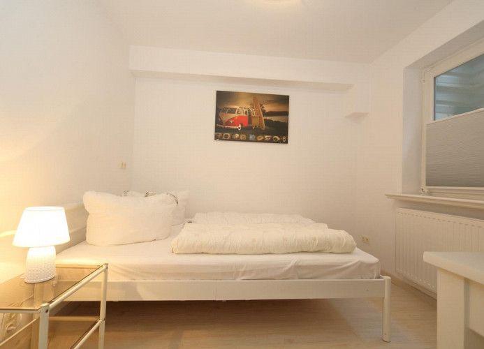 Schlafzimmer mit weißem Bett, Lampe und Wandbild