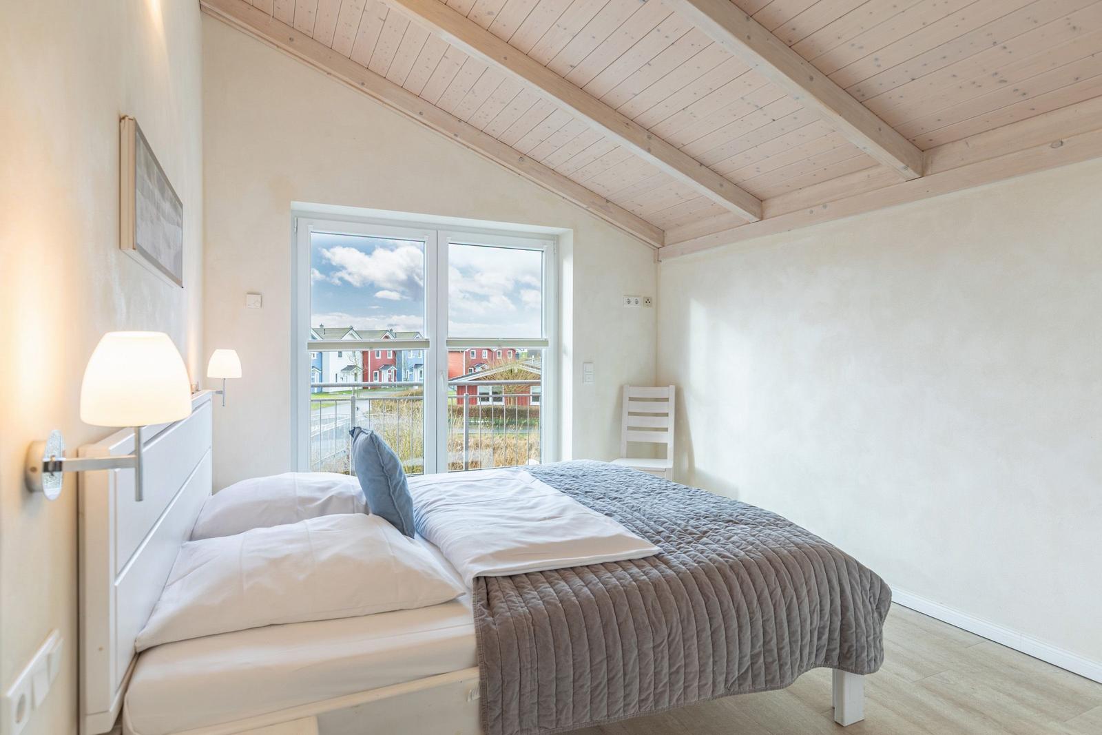 Schlafzimmer mit Bett, Fenster und Holzdach
