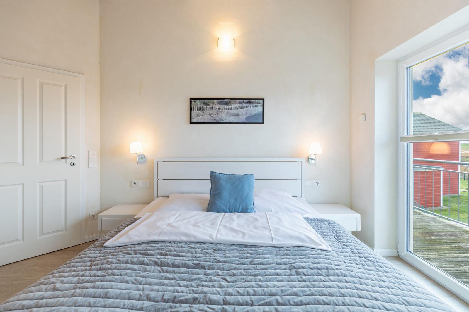 Schlafzimmer mit Bett, Nachttischen und Balkontür.