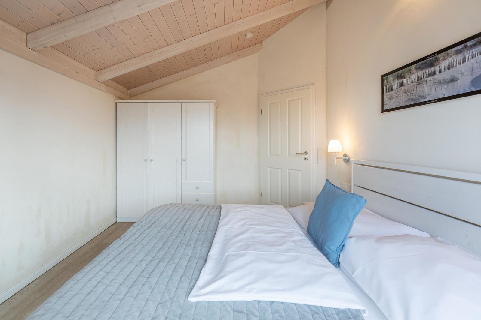 Schlafzimmer mit Bett, Kleiderschrank und Wandbild.