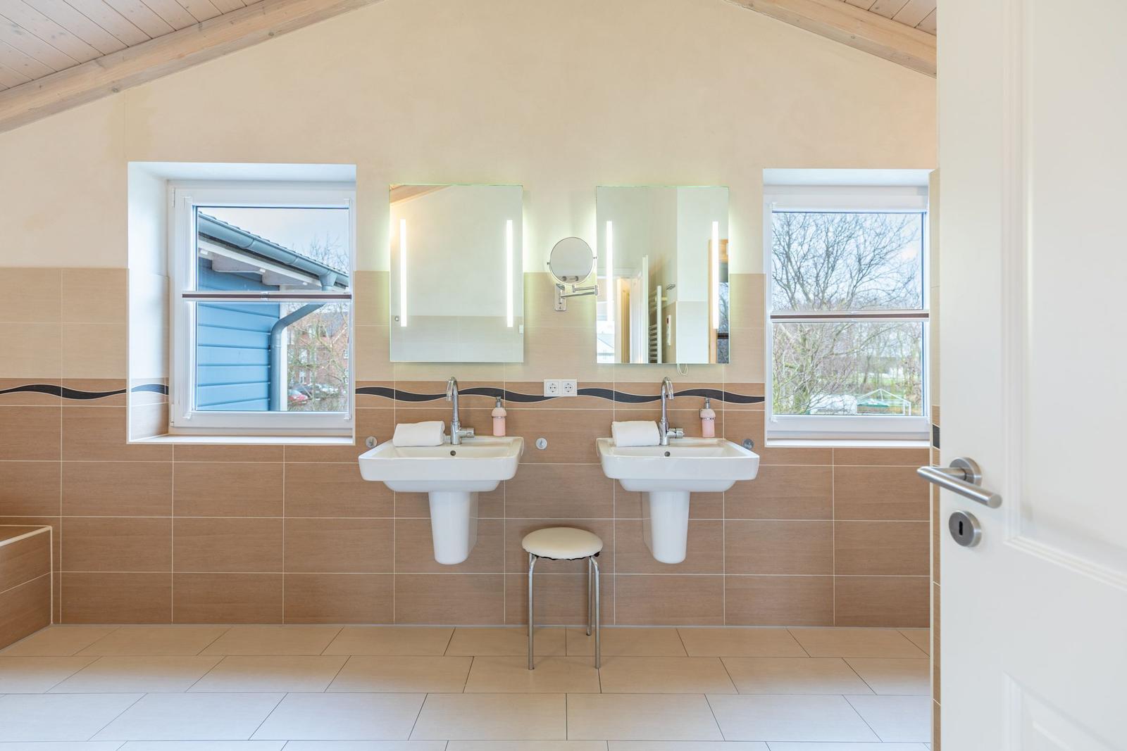 Zwei Waschbecken mit Spiegeln und Fenstern an der Wand.
