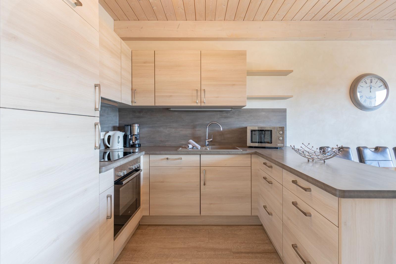 Küche mit Holzmöbeln, Spüle, Herd und Mikrowelle