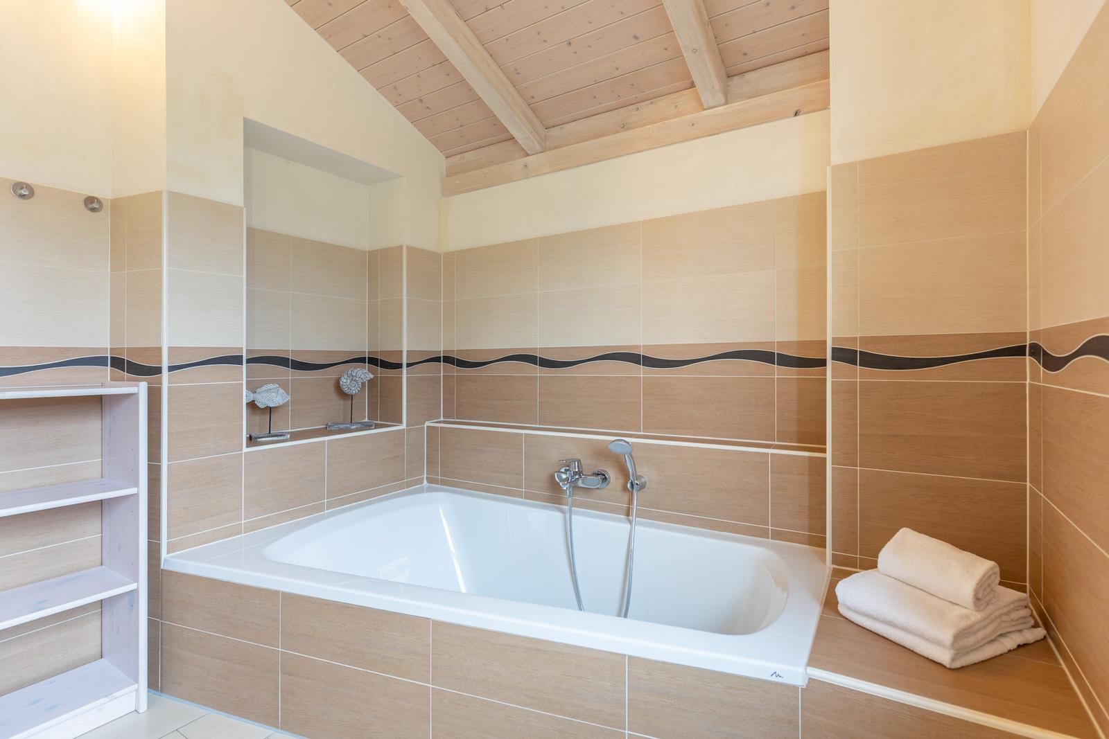 Bad mit Badewanne, Holzdecke und Handtuchstapel