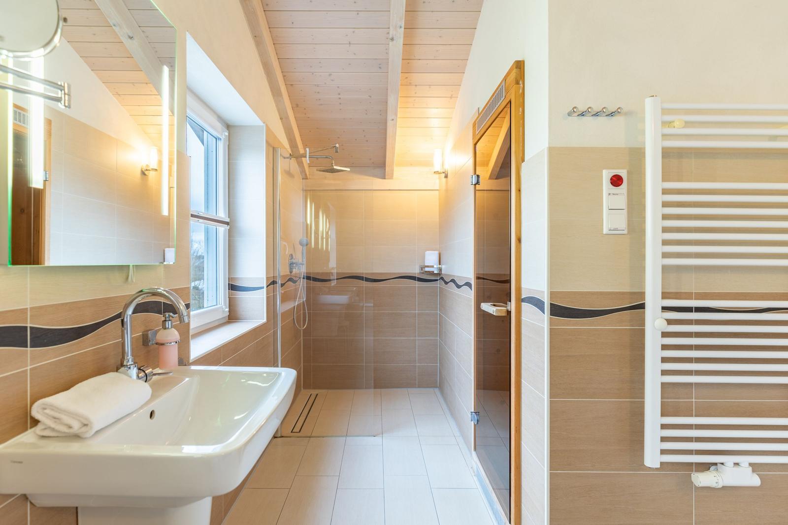 Badezimmer mit Dusche, Waschbecken und Heizkörper.