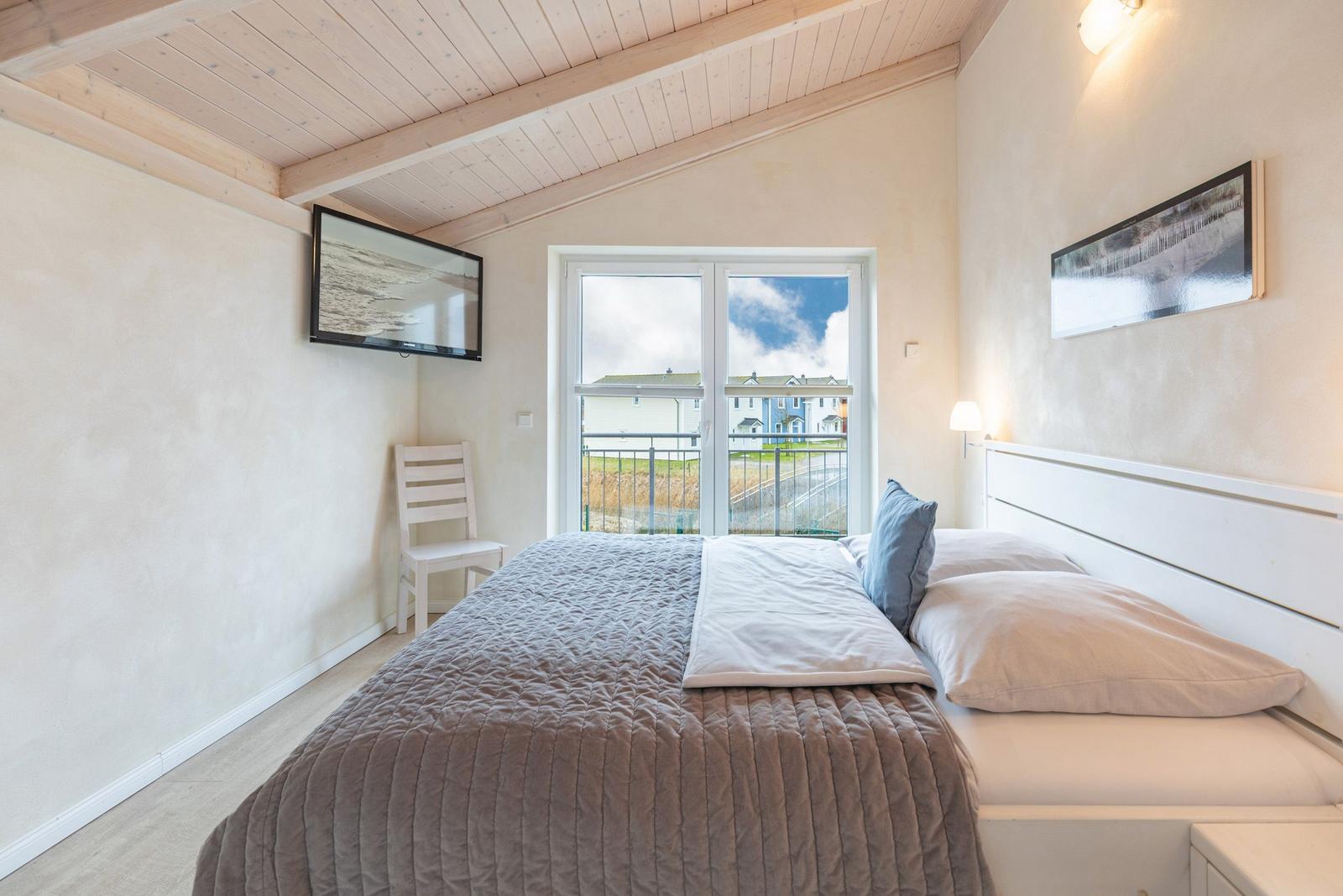 Schlafzimmer mit Bett, Fenster und Wandbildern.