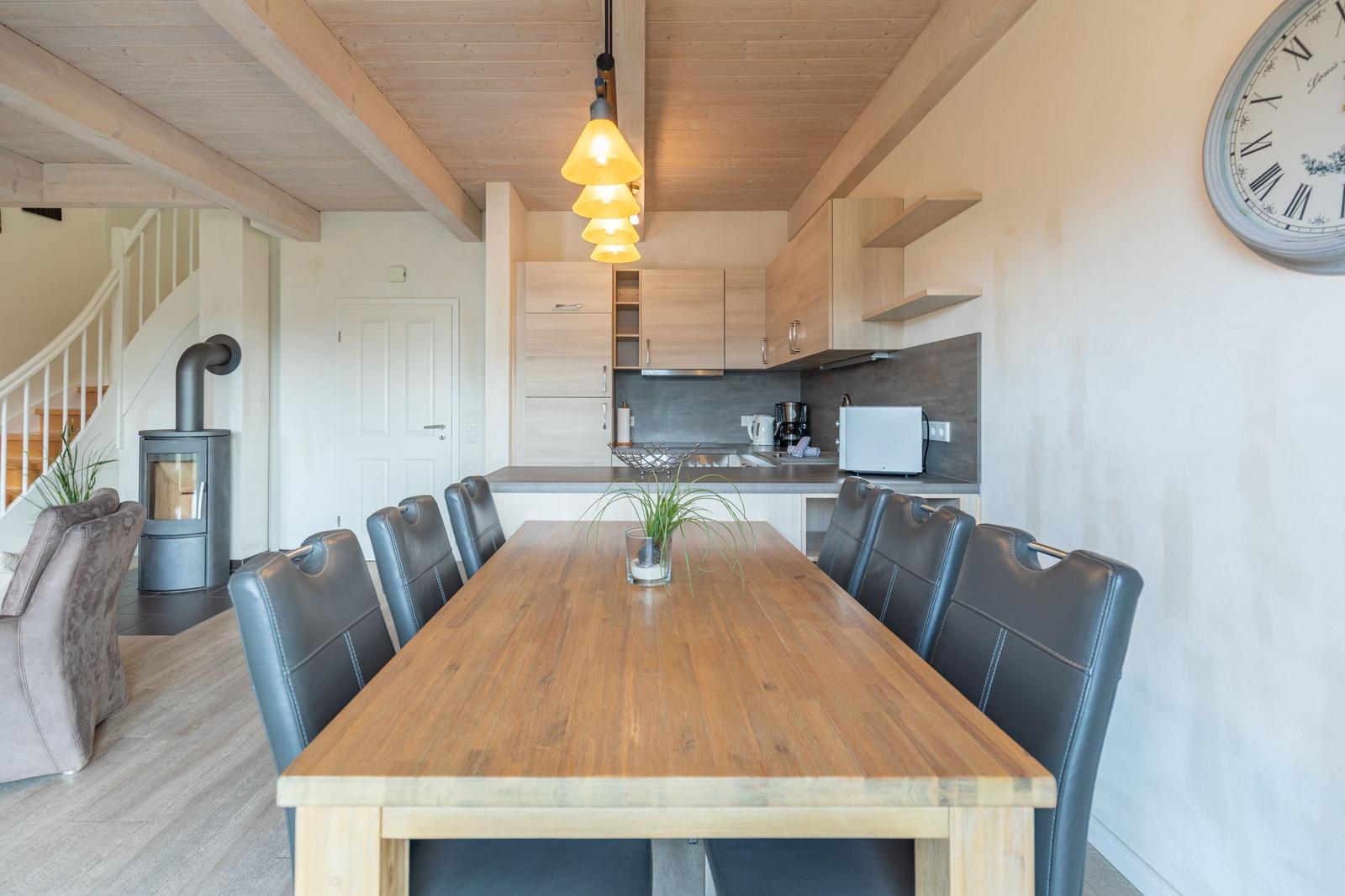 Esszimmer mit Holztisch, Stühlen und Küchenbereich im Hintergrund.