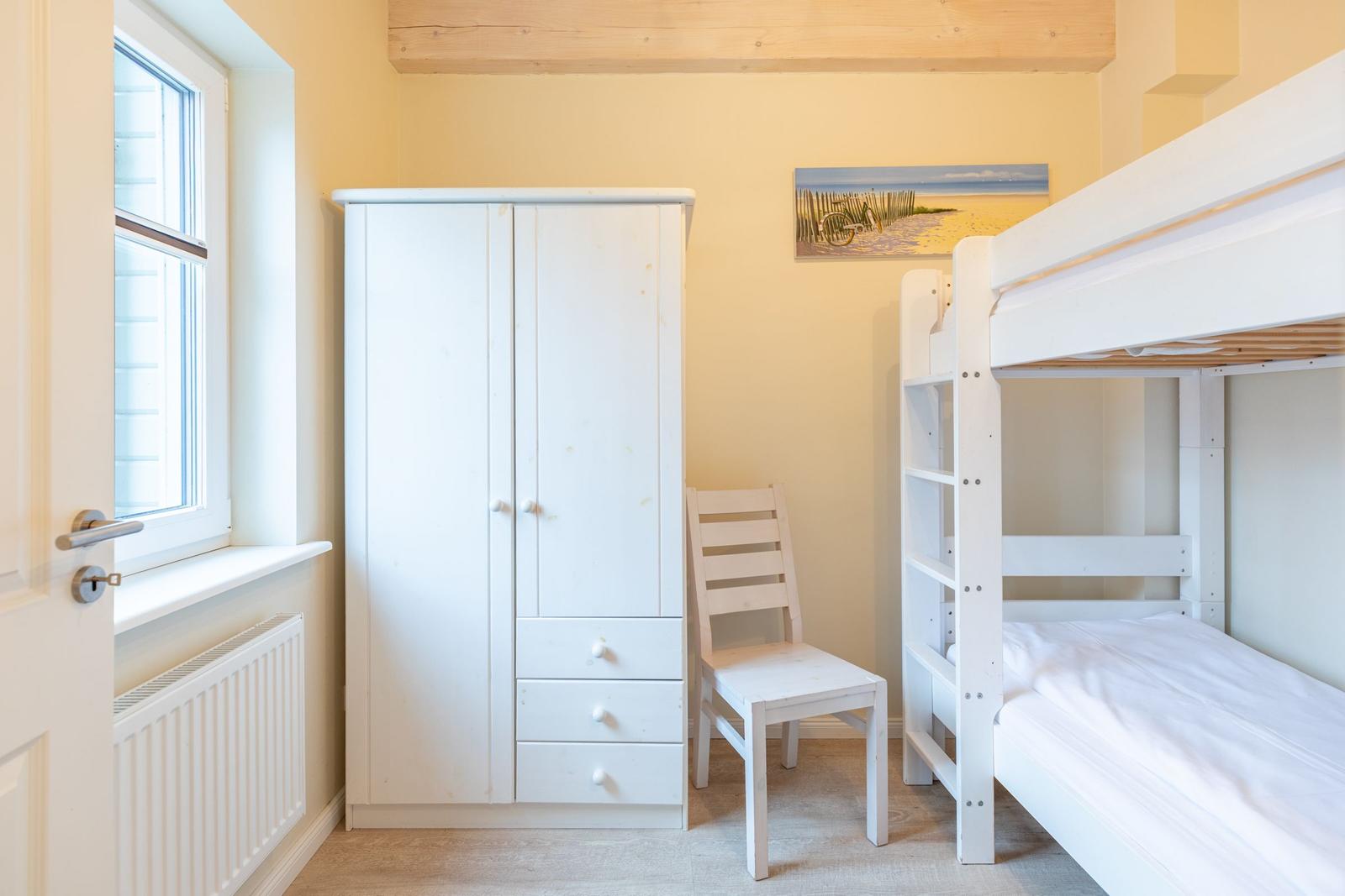 Zimmer mit Doppelstockbett, Kleiderschrank und Stuhl. Wandbild und Holzbalken.