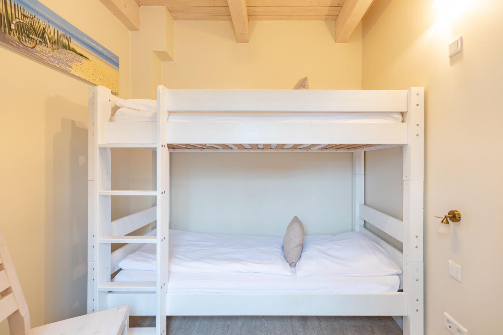 Zimmer mit weißem Doppelstockbett, Holzbalkendecke und Wandbild.