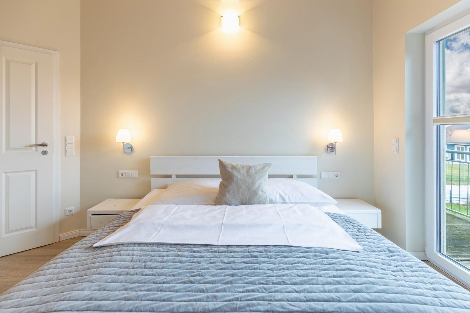 Schlafzimmer mit Doppelbett, Nachttischen und Fensterblick.