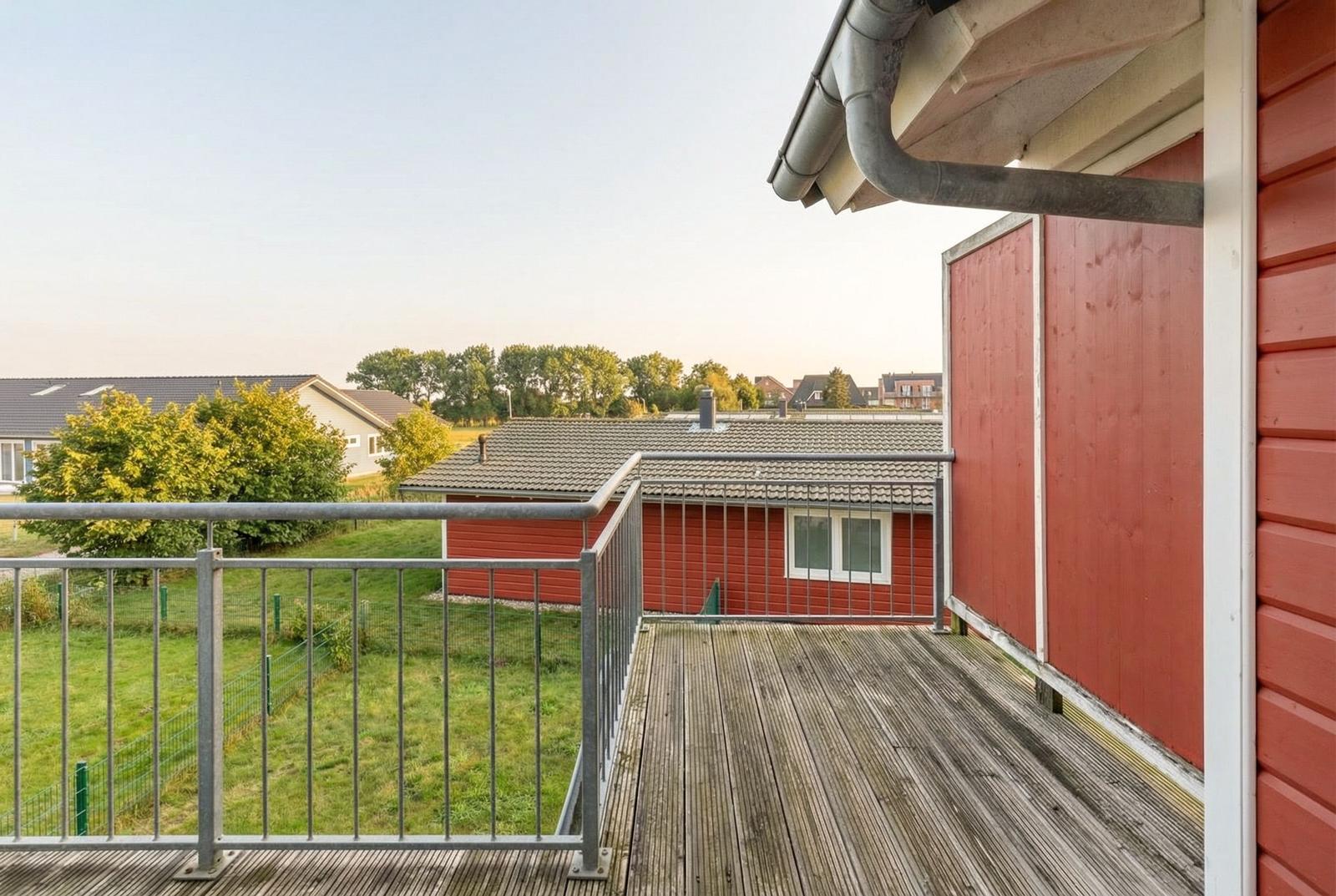 Terrasse mit Blick auf grüne Wiesen und rote Häuser.