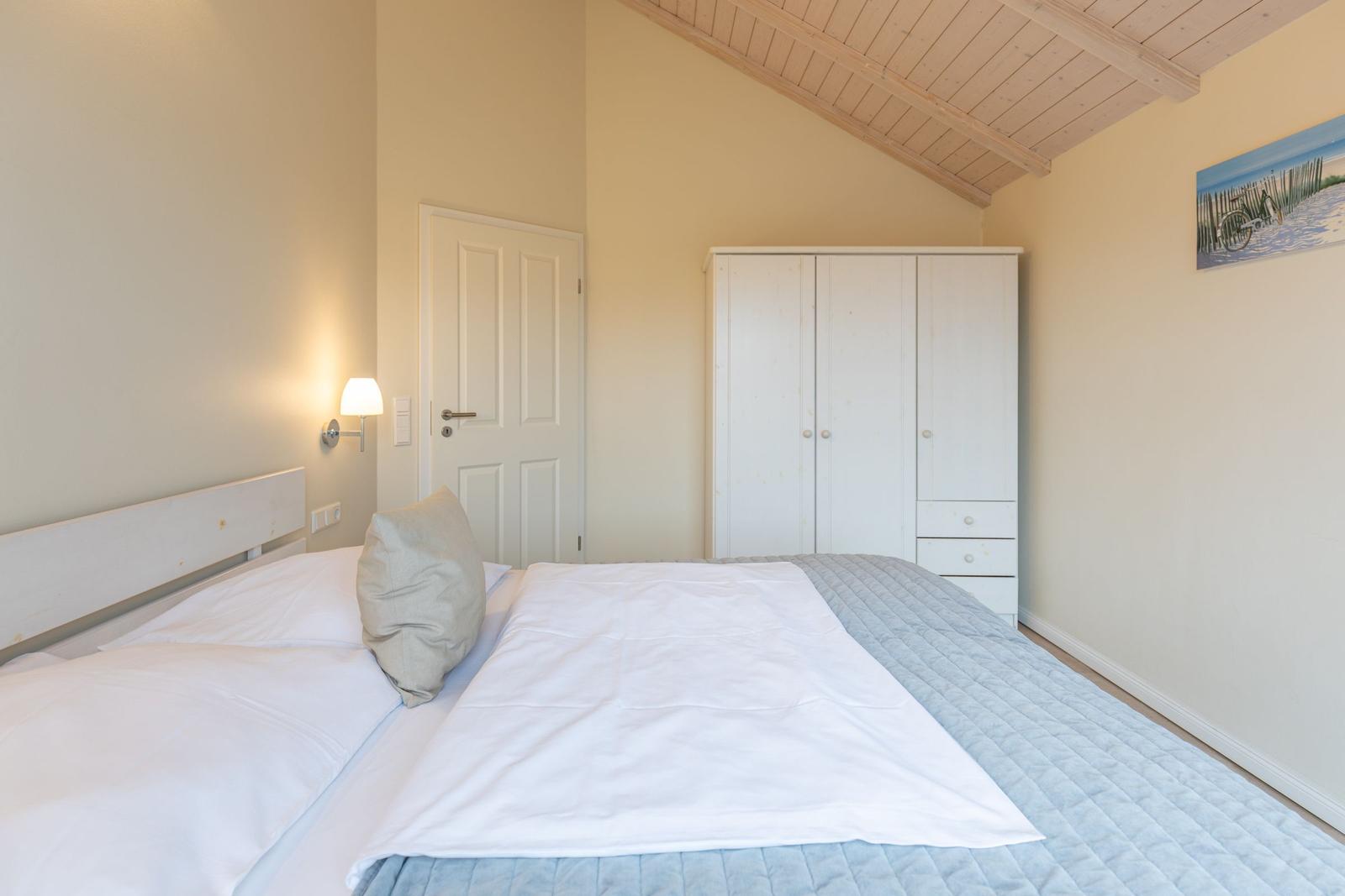 Schlafzimmer mit Bett, Kleiderschrank und Wandbild.