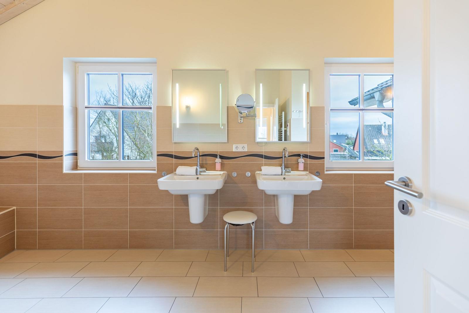 Zwei Waschbecken mit Spiegeln und Fenstern an der Wand.