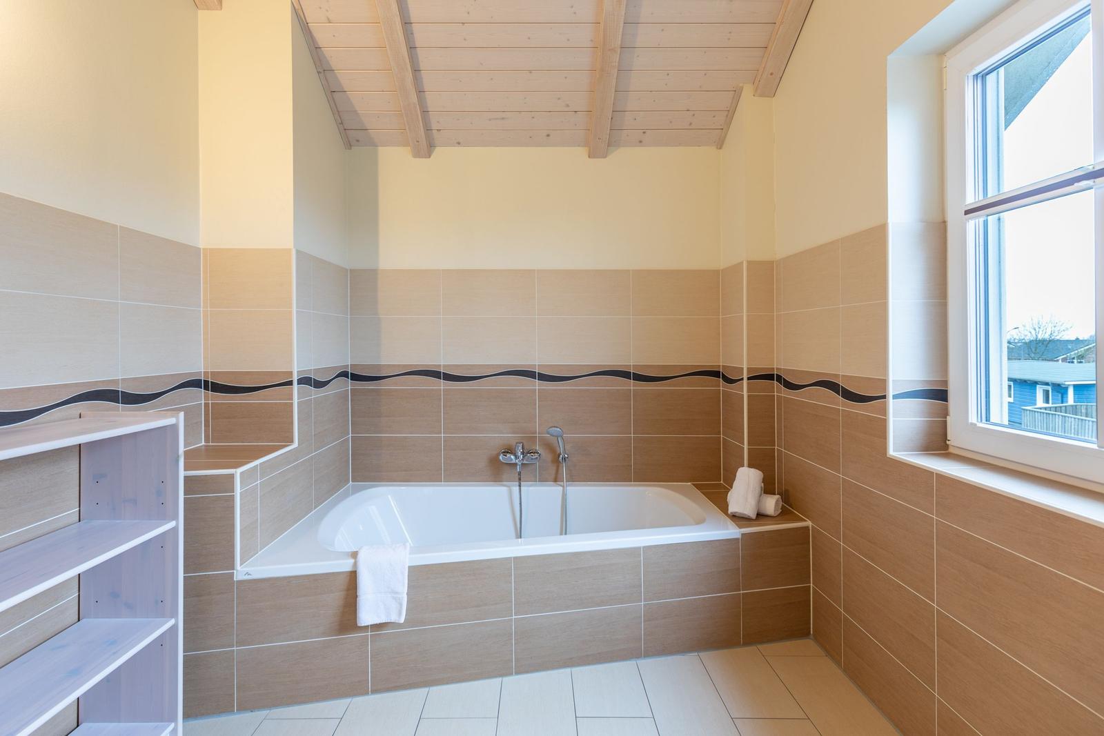Bad mit Badewanne, Fenster und Holzdecke.