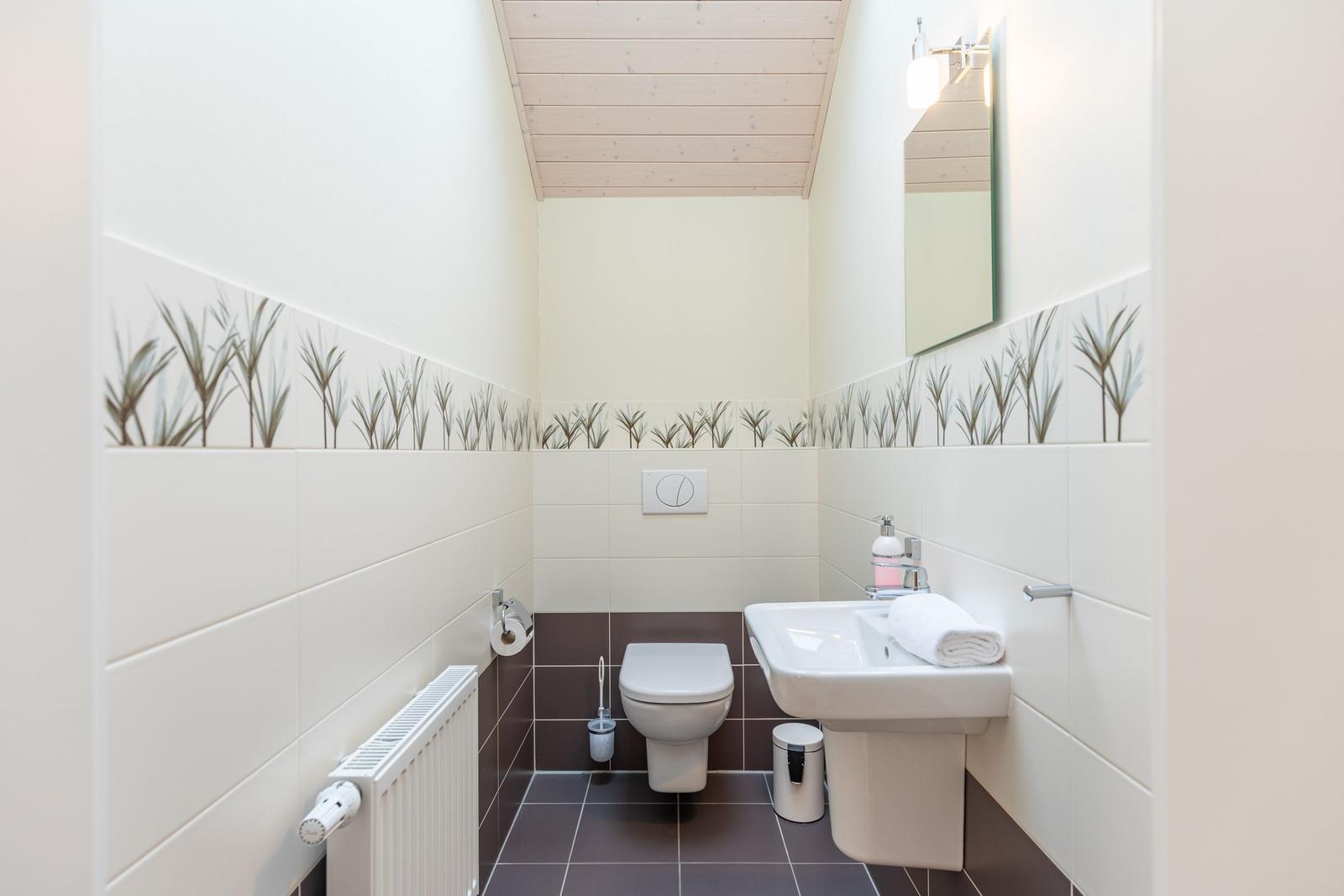 Badezimmer mit Toilette, Waschbecken und Spiegel an der Wand.