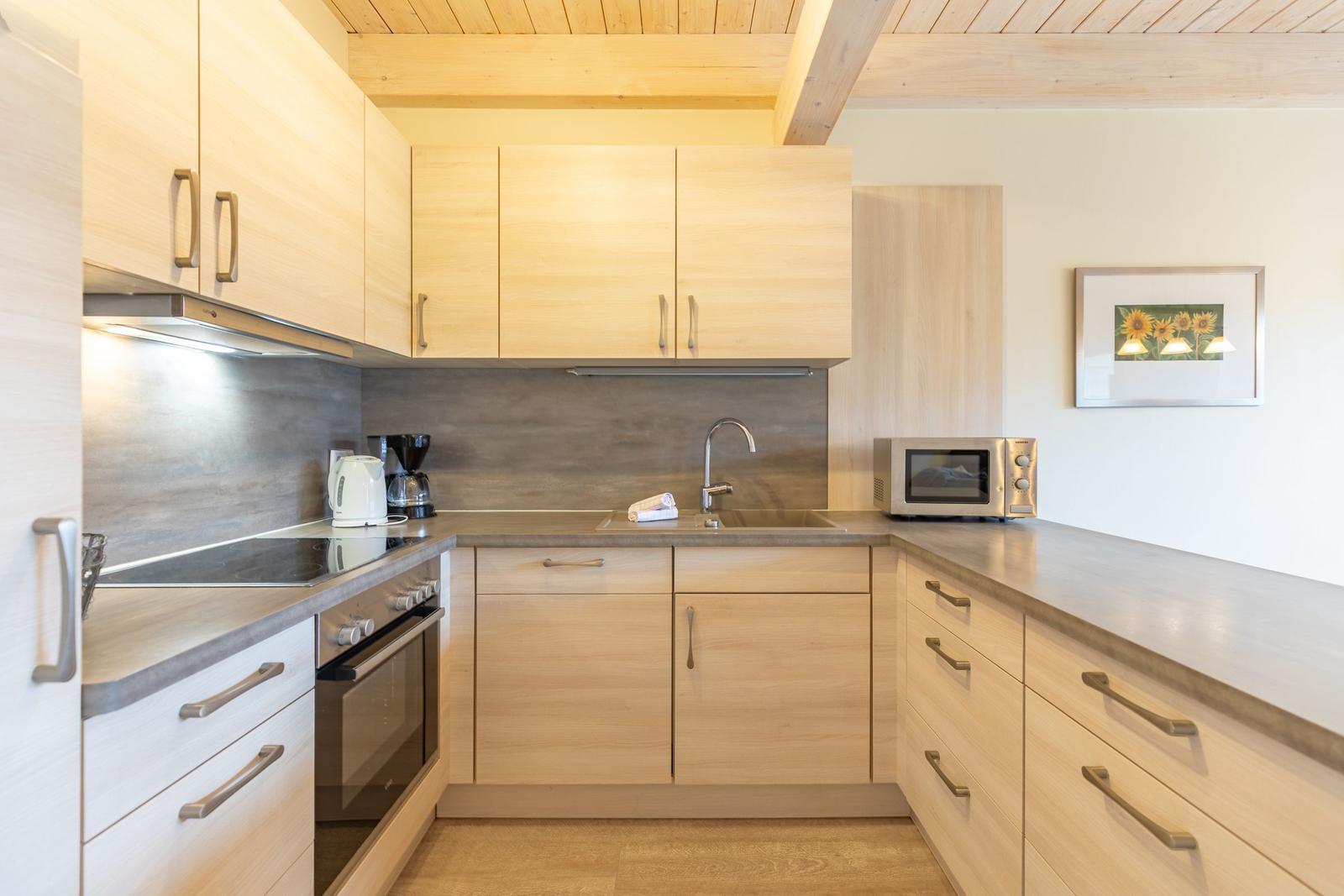 Moderne Küche mit Holzschränken, Spüle und Kochfeld.