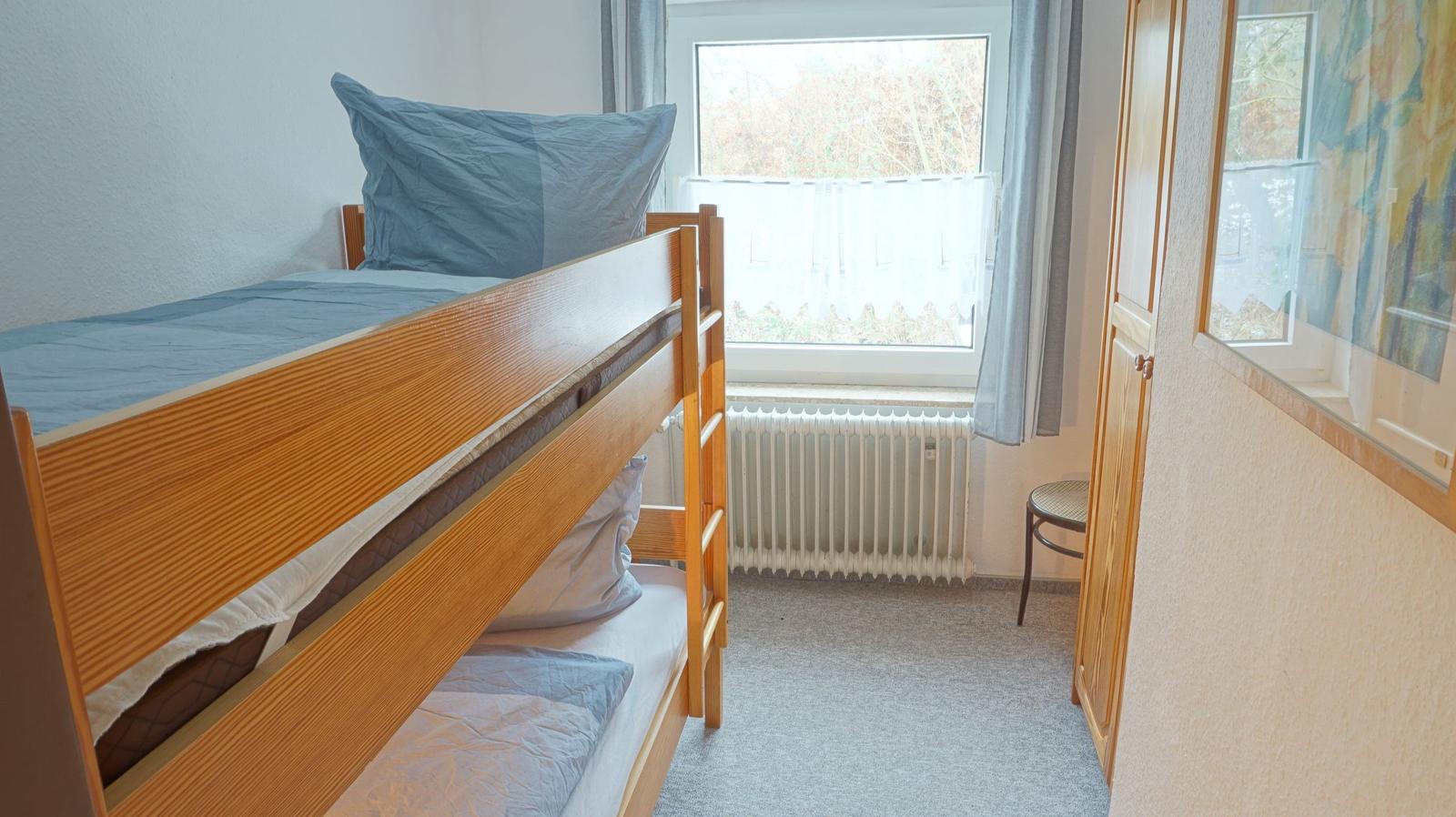 Ein Schlafzimmer mit einem Doppelstockbett, einem Fenster und einem Kleiderschrank.