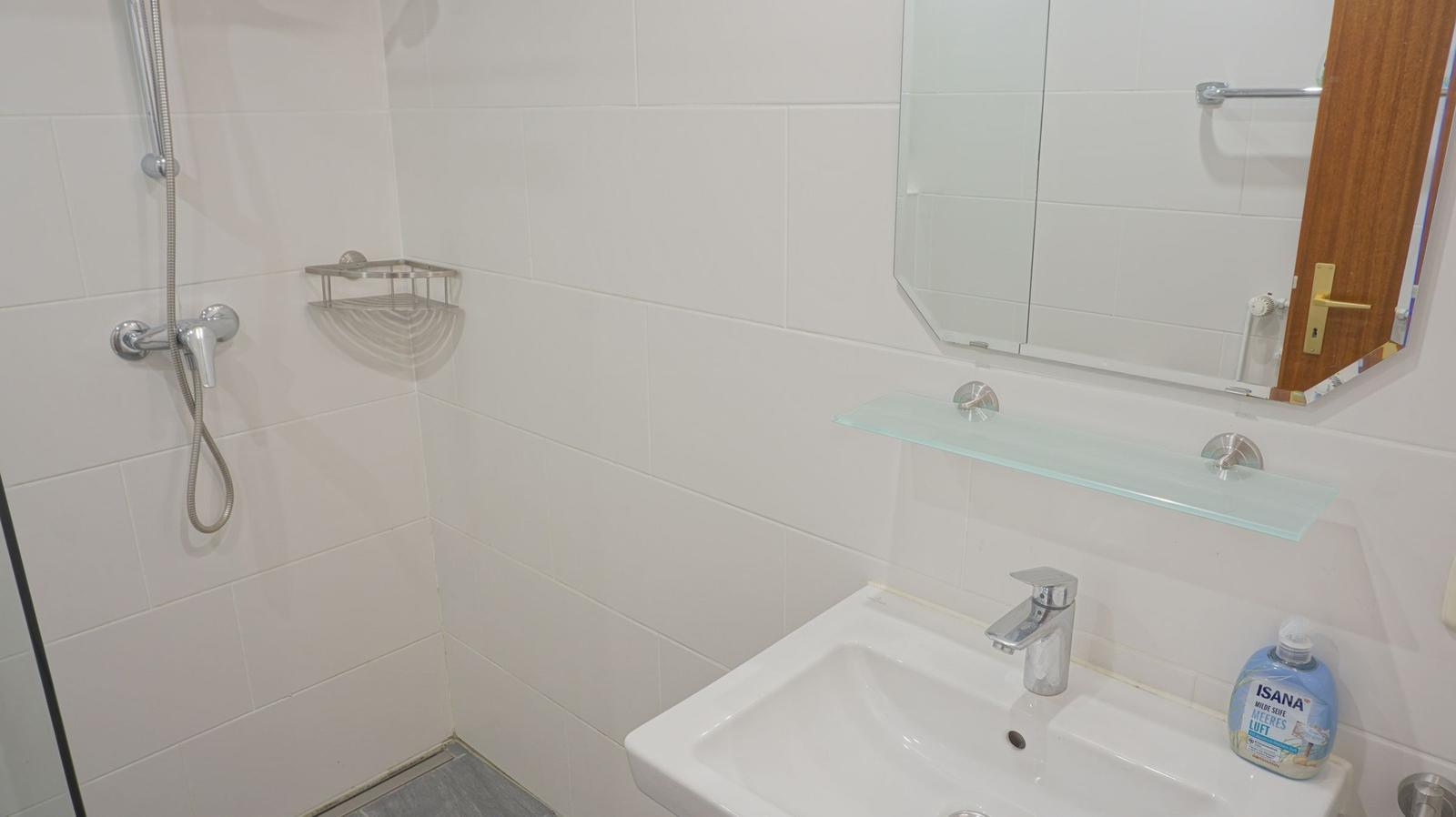 Bad mit Dusche, Waschbecken und Spiegel