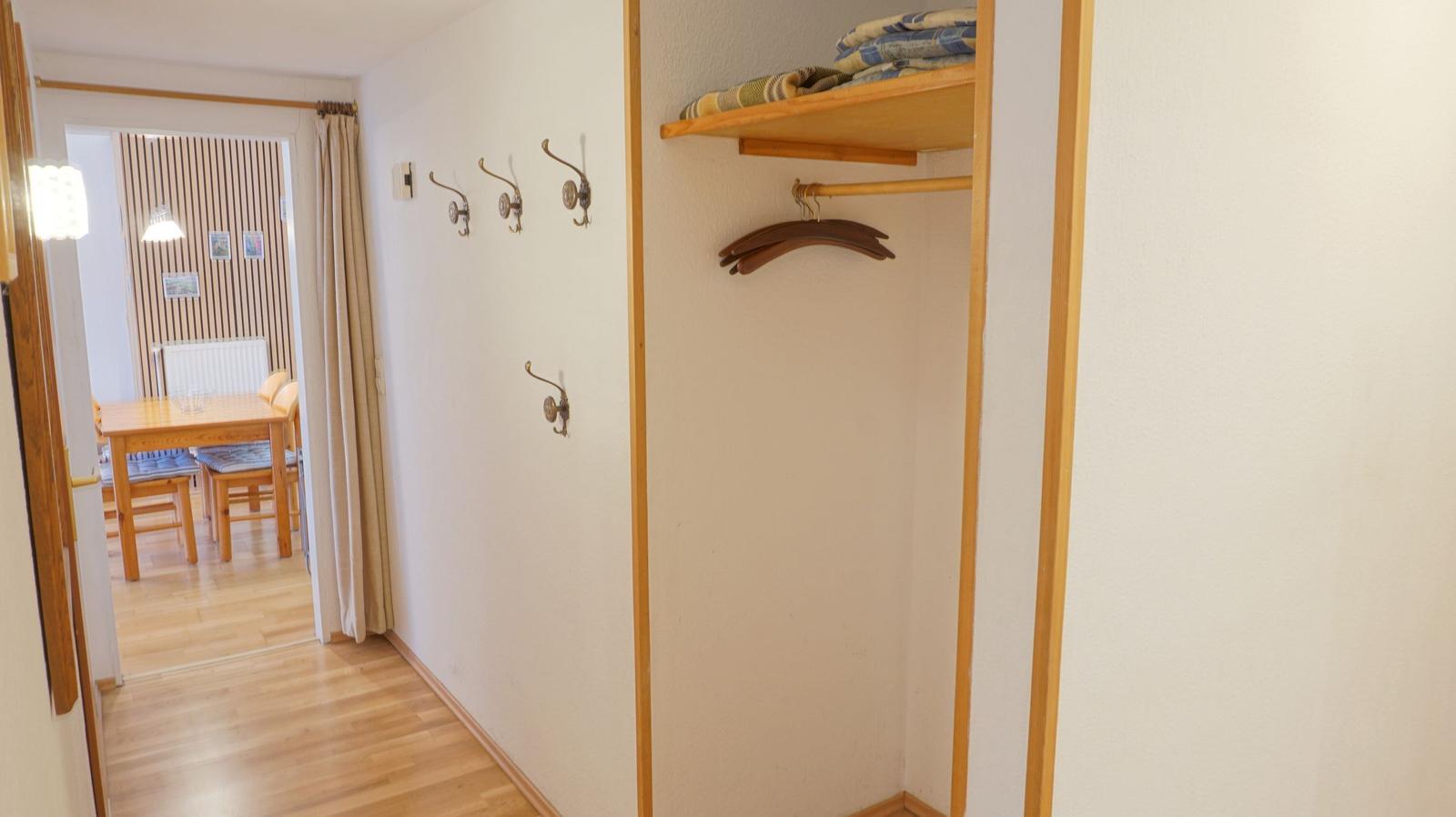 Flur mit Kleiderständer und Haken. Durchgang zum Esszimmer mit Tisch und Stühlen.