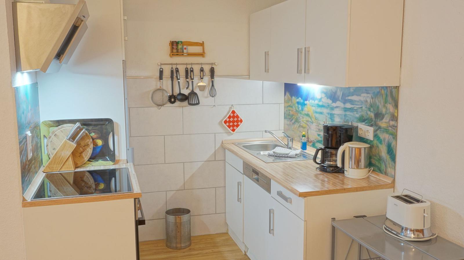 Küche mit Spüle, Kochfeld, Kaffeemaschine und Toaster.