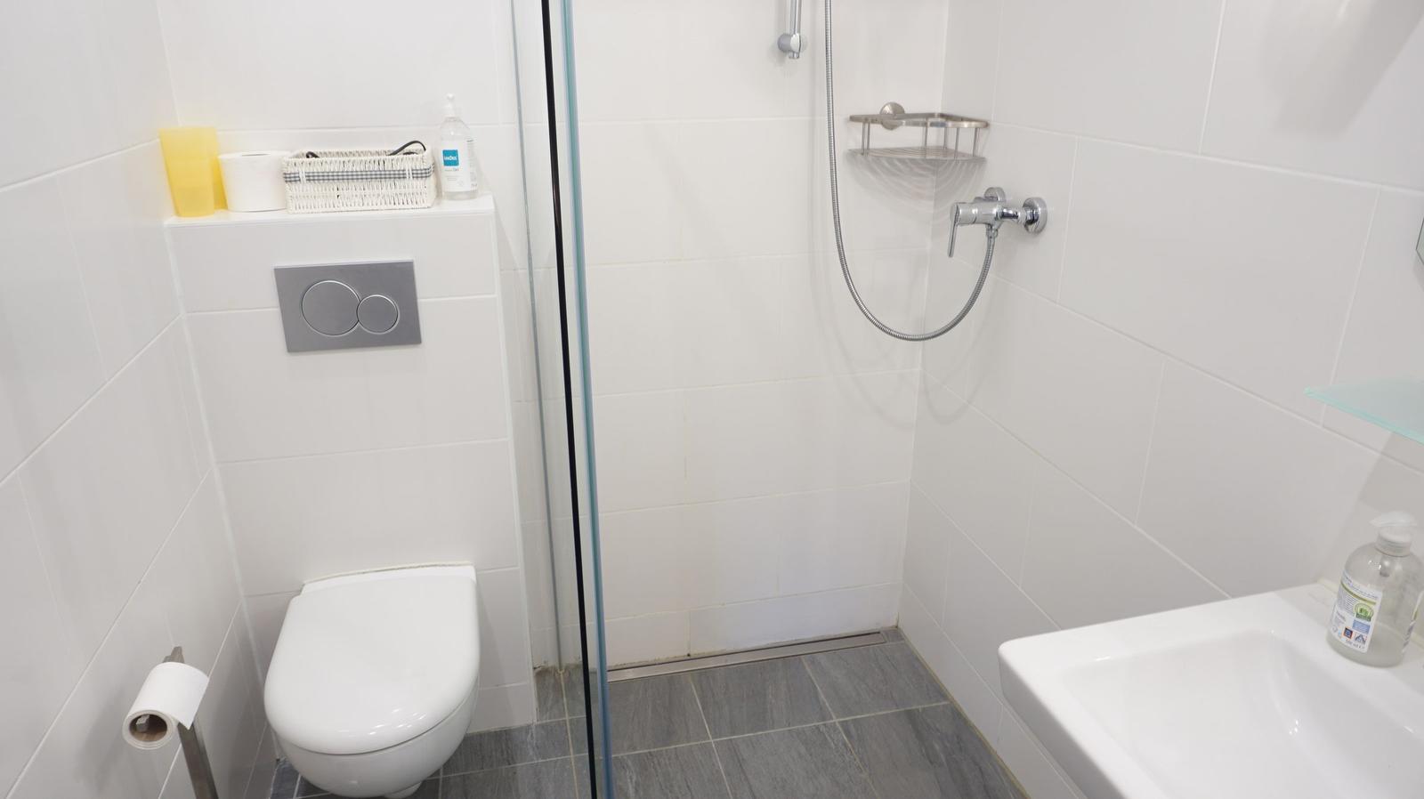 Badezimmer mit Dusche, Toilette und Waschbecken.