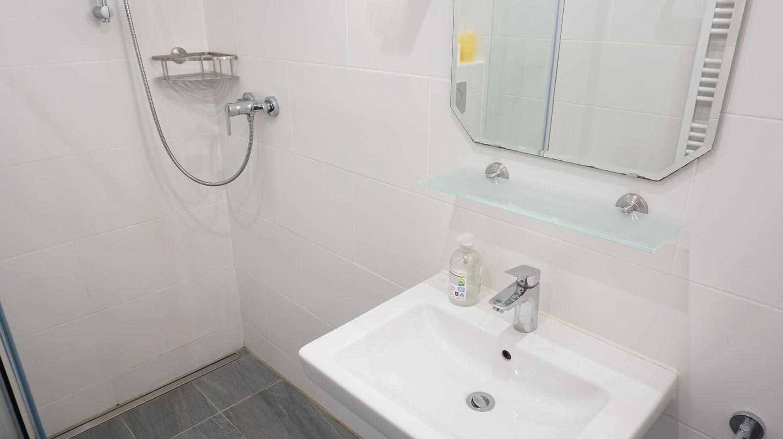 Badezimmer mit Dusche, Waschbecken und Spiegel