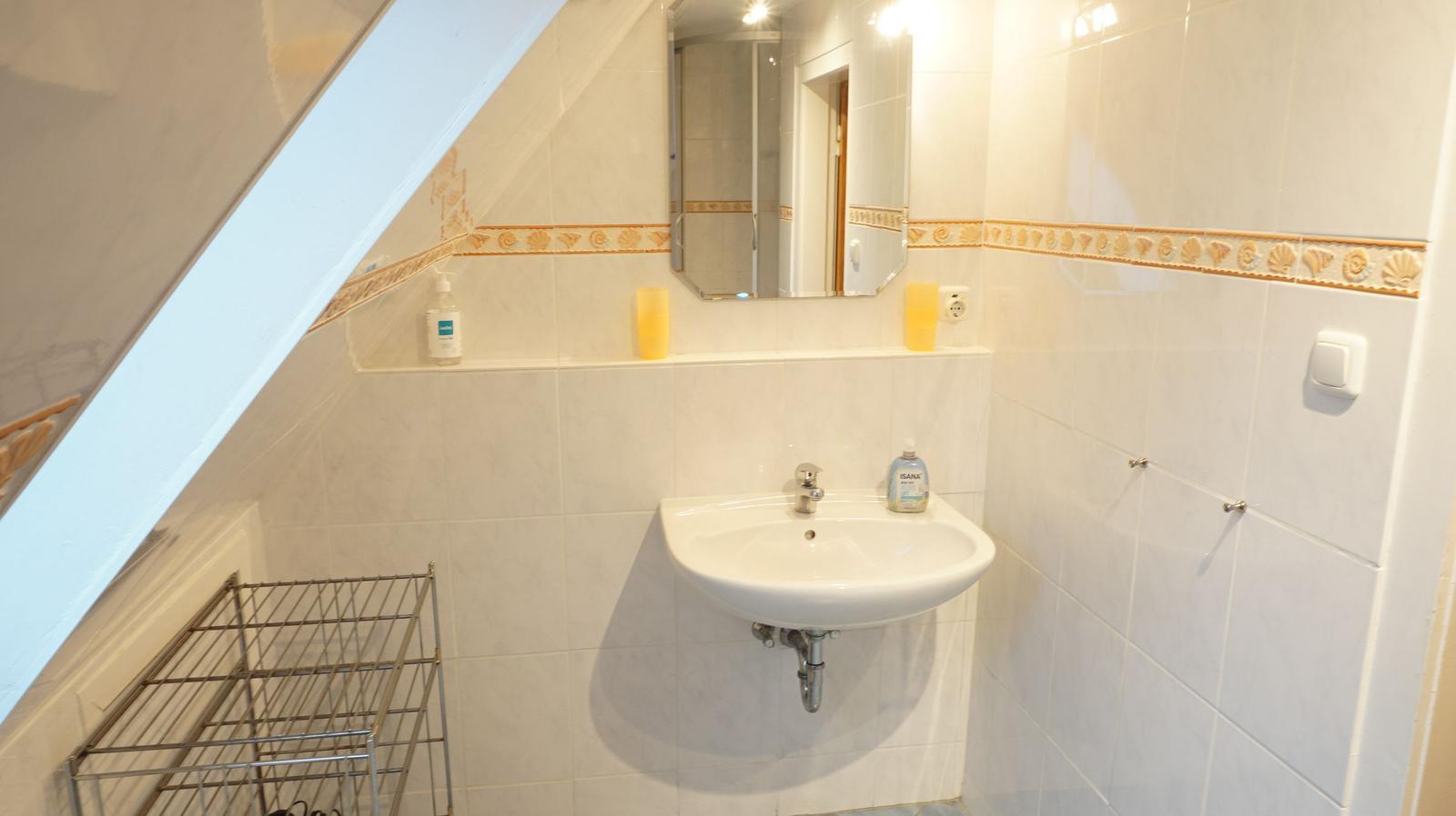 Badezimmer mit Waschbecken, Spiegel und Dusche unter Dachschräge