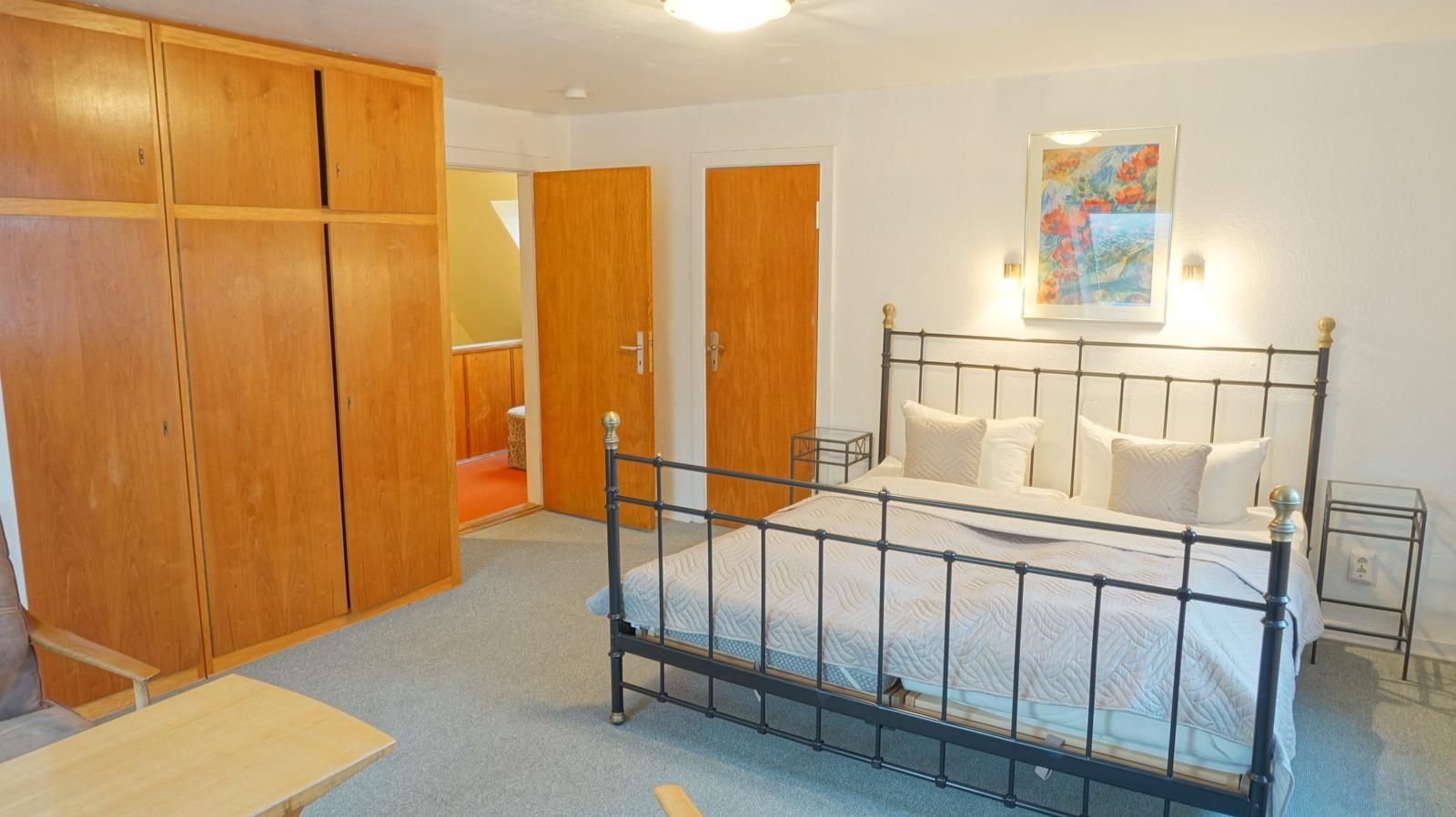 Schlafzimmer mit Bett, Kleiderschrank und Wandbild.