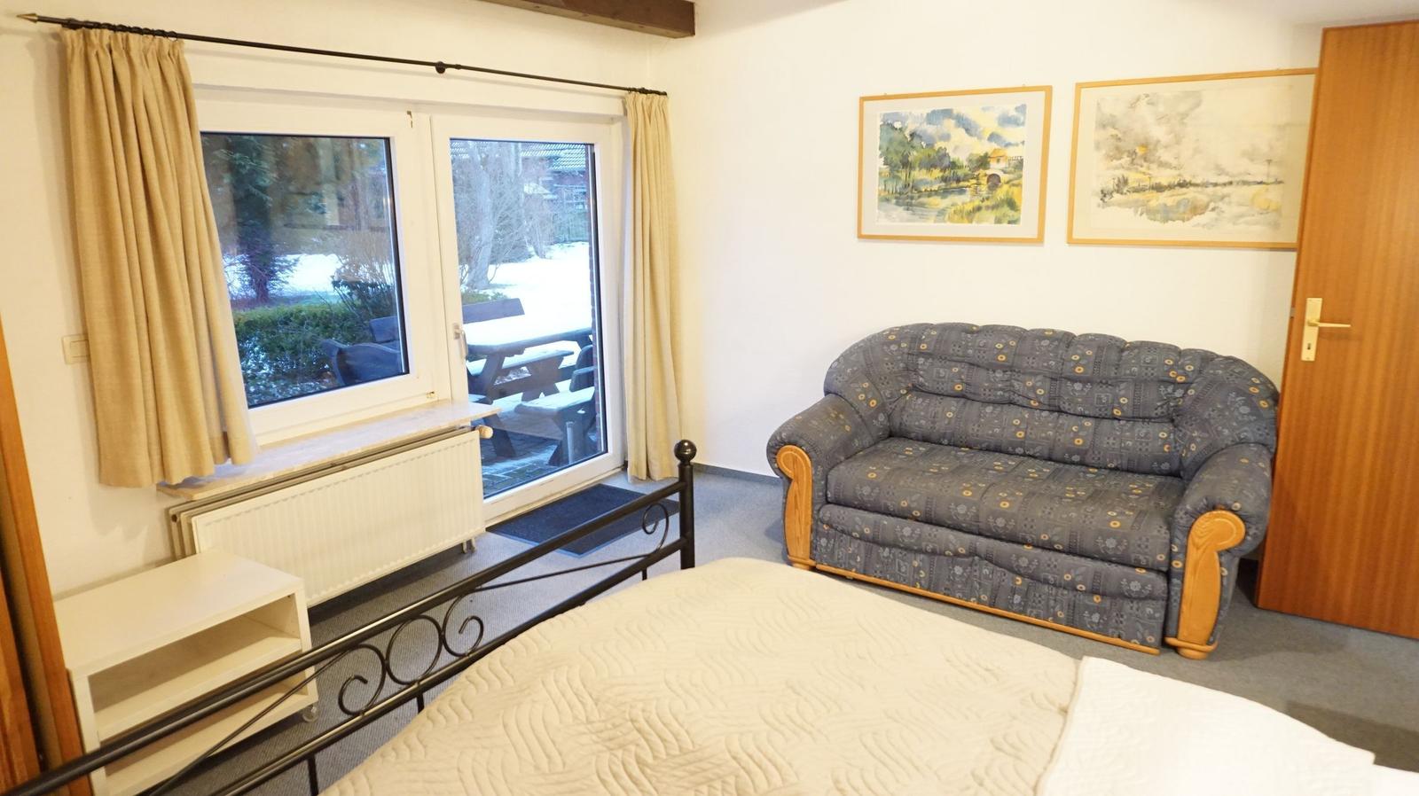 Zimmer mit Bett, Sofa, Fenster und Tür