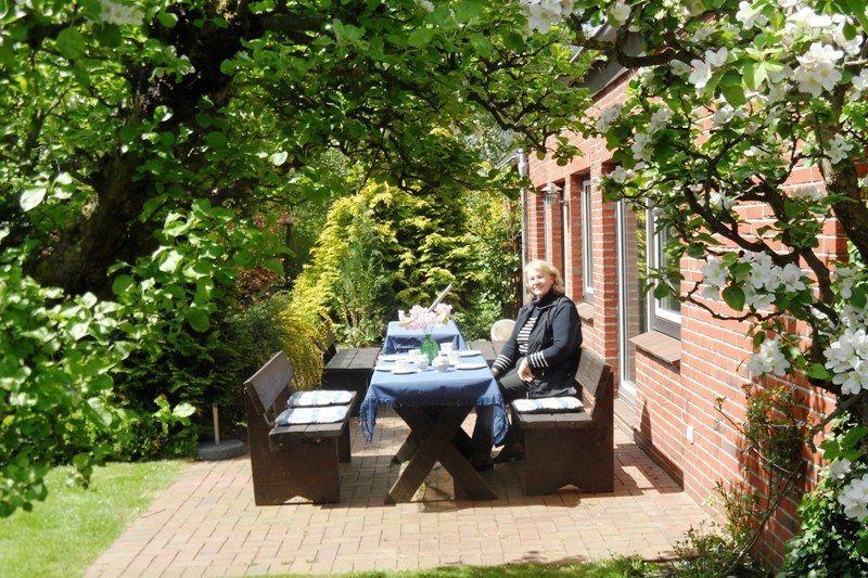 Garten mit Tisch, Bänken und Blühenden Bäumen neben Backsteinhaus