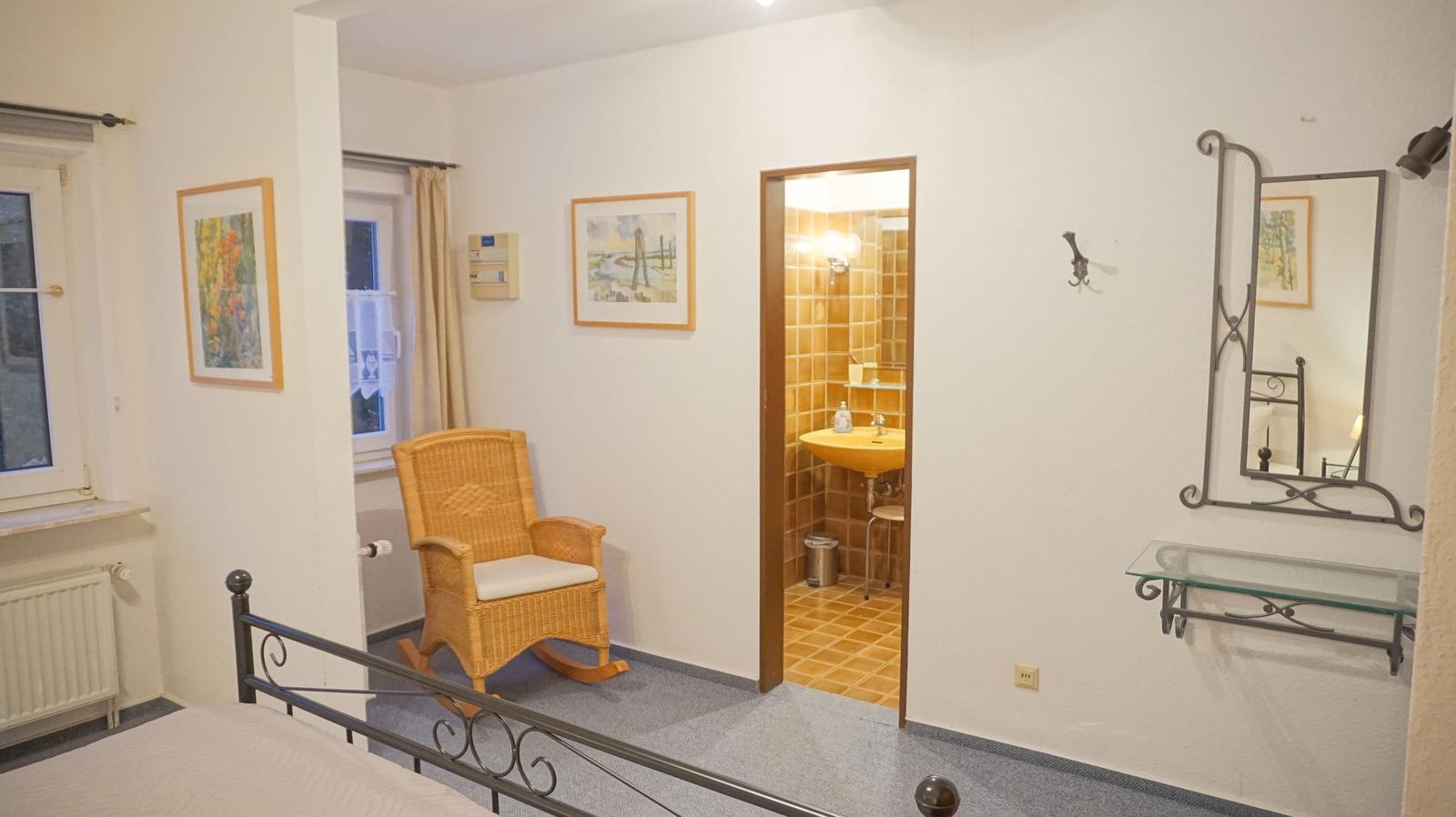 Schlafzimmer mit Blick auf Bad, Wicker-Stuhl und Spiegel