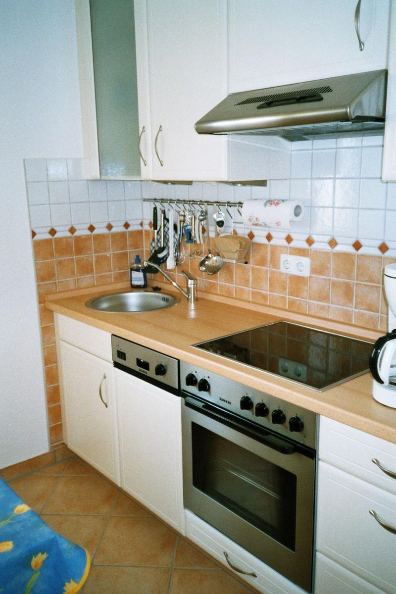 Küche mit Spüle, Herd und Backofen. Arbeitsfläche aus Holz.