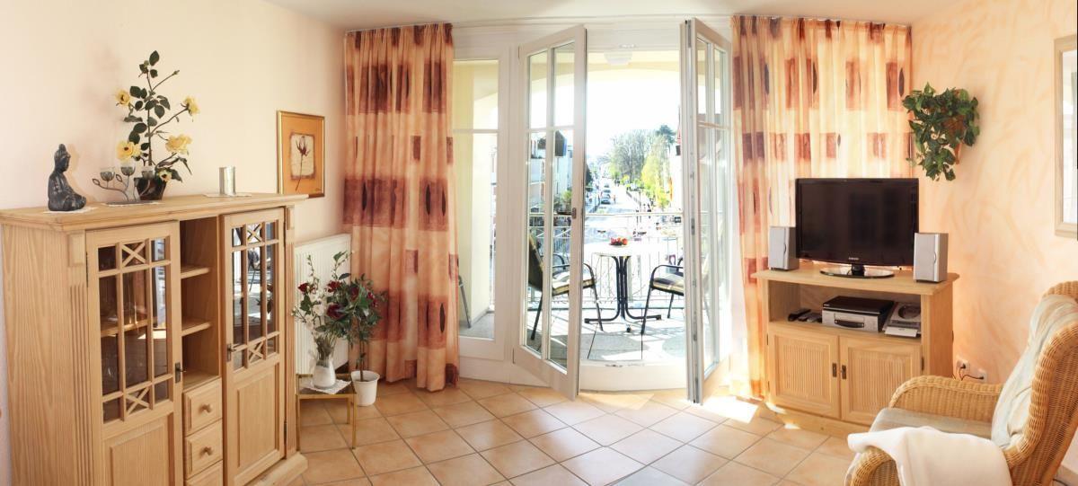 Wohnzimmer mit TV, Schrank und Balkonzugang.